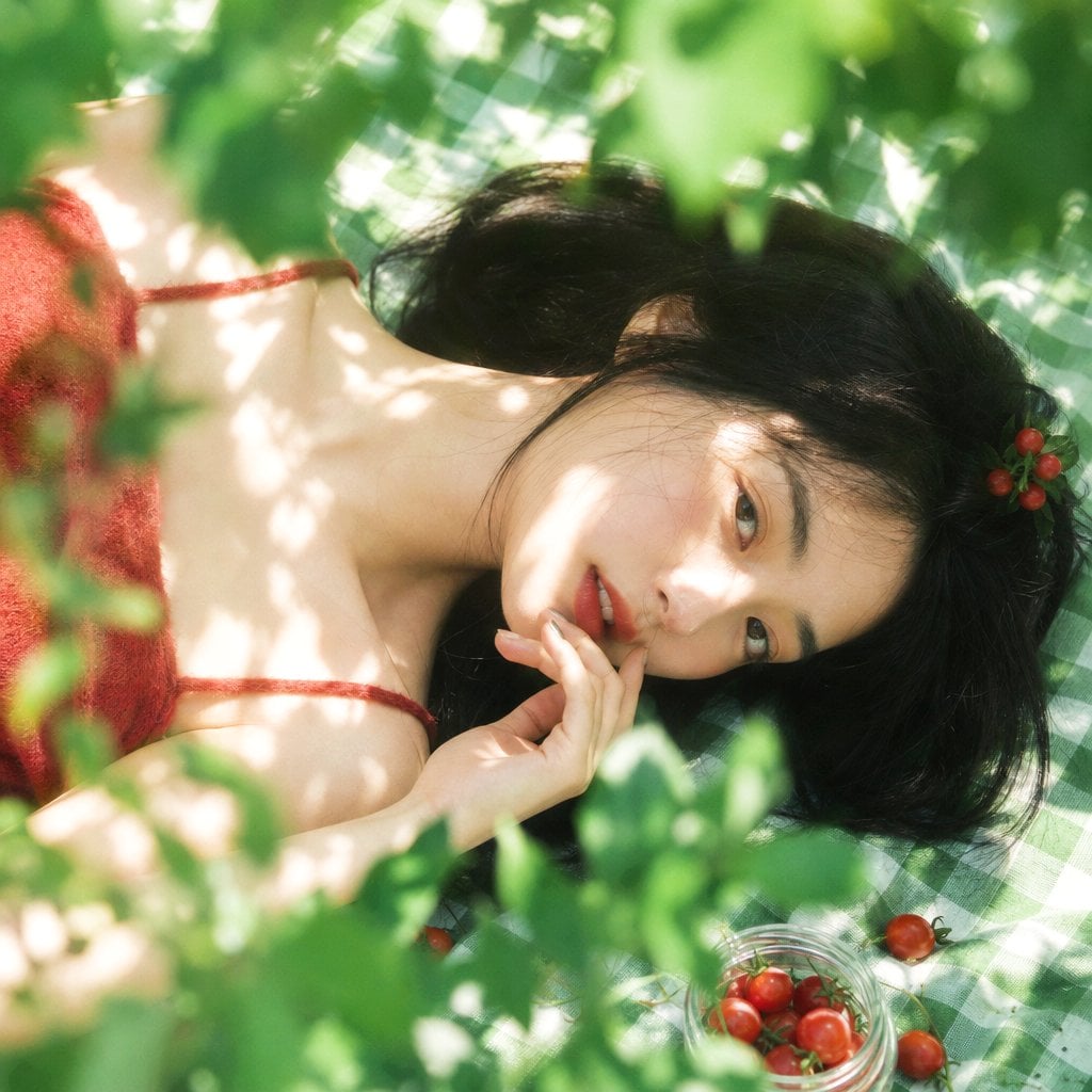 真人摄影，夏日植物系生活方式写真，清透日系胶片感，竖幅 2:3，俯拍近景到面部特写，年轻女性横向躺在绿白格纹野餐布上，脸部位于画面中部偏右下作…
