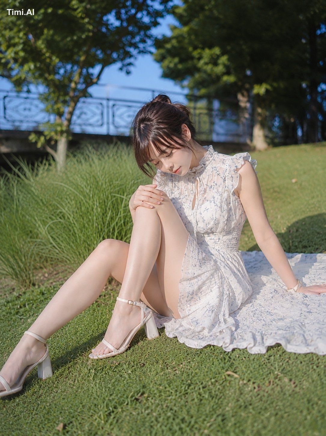 縦位置の写真。緑豊かな公園の芝生に、ひとりの女性が画面中央やや右寄りに座っている。人物は全身が入る大きさで、画面の約7割を占める。左脚を前方へ…