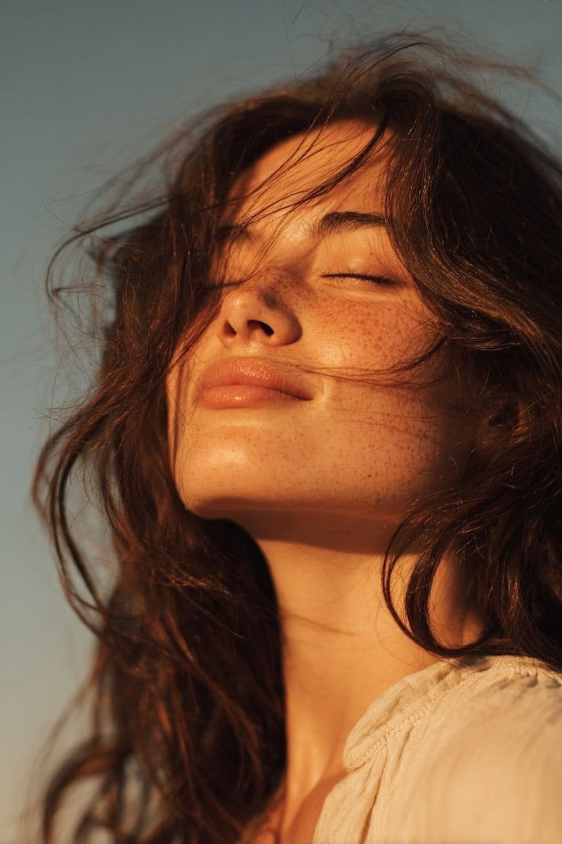 Ultra-realistic golden hour close-up portrait of a young woman outdoors…