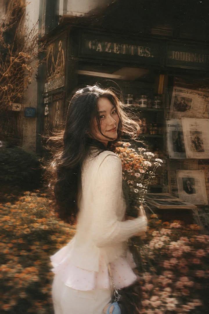 A beautiful young woman with long dark flowing hair holding a bouquet o…