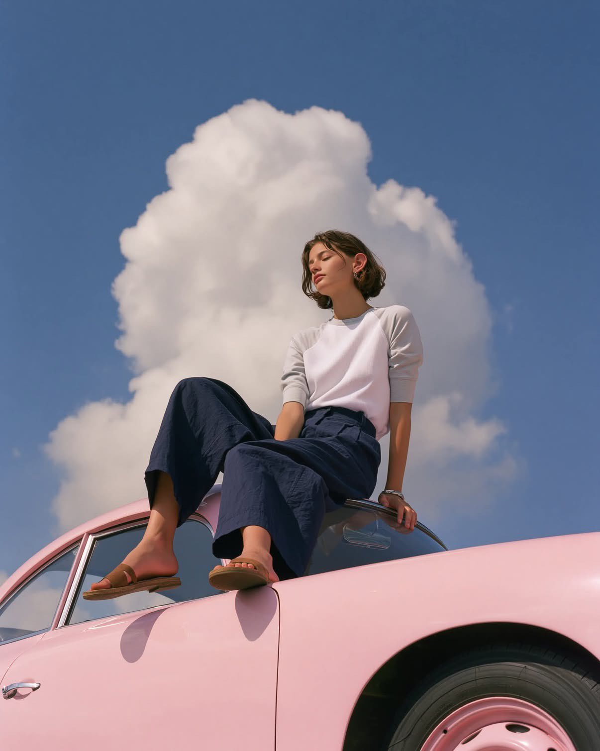 A dreamy editorial fashion photograph of a minimalist young woman sitti…
