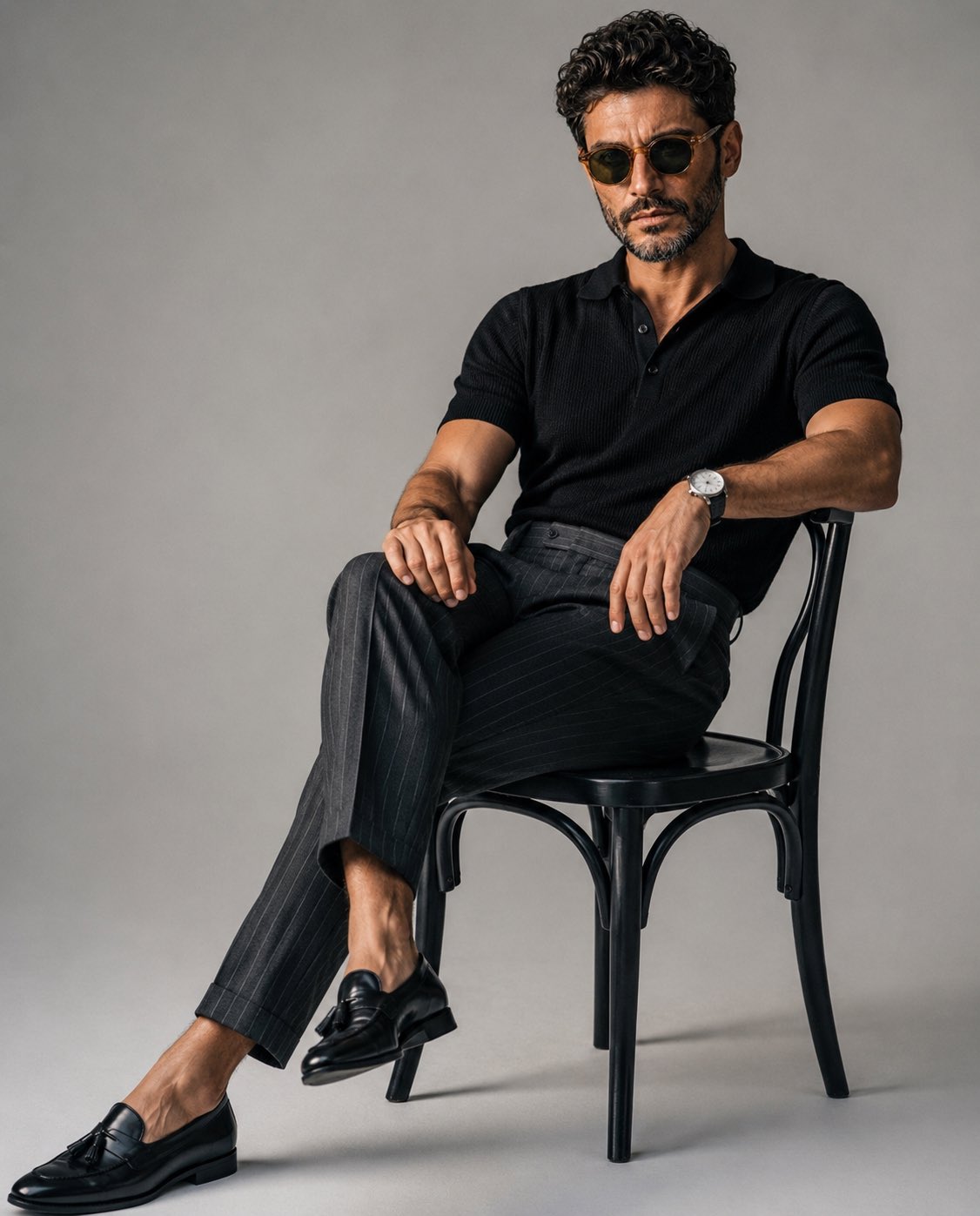 A luxury editorial fashion portrait of a stylish young man sitting casu…