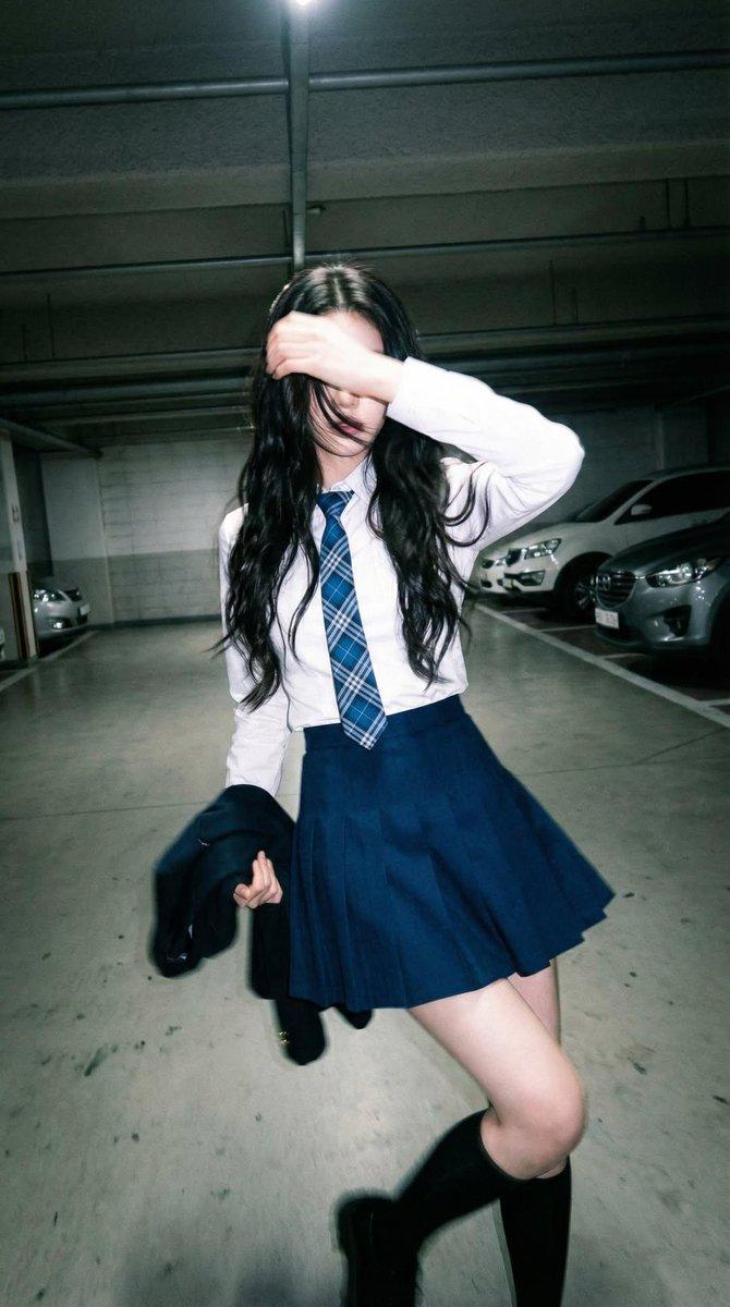 Candid portrait of a young woman in a dim parking garage, wearing a whi… 1