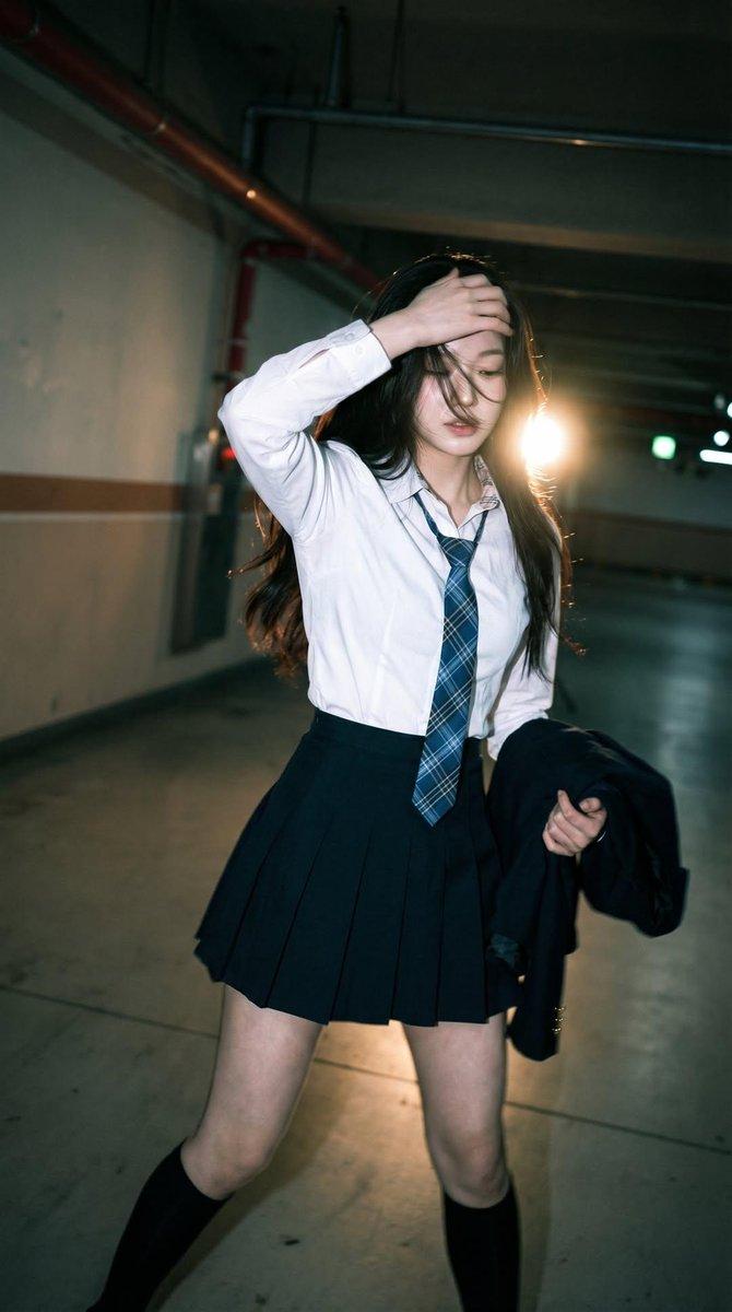 Candid portrait of a young woman in a dim parking garage, wearing a whi… 2