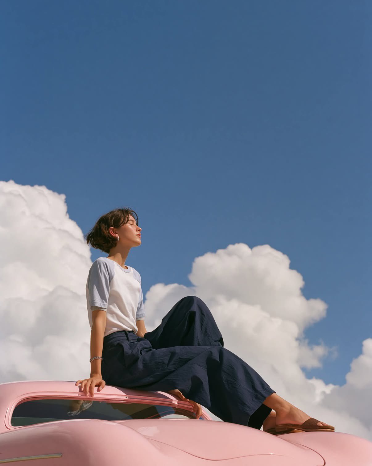 A dreamy editorial fashion photograph of a minimalist young woman sitti… 1