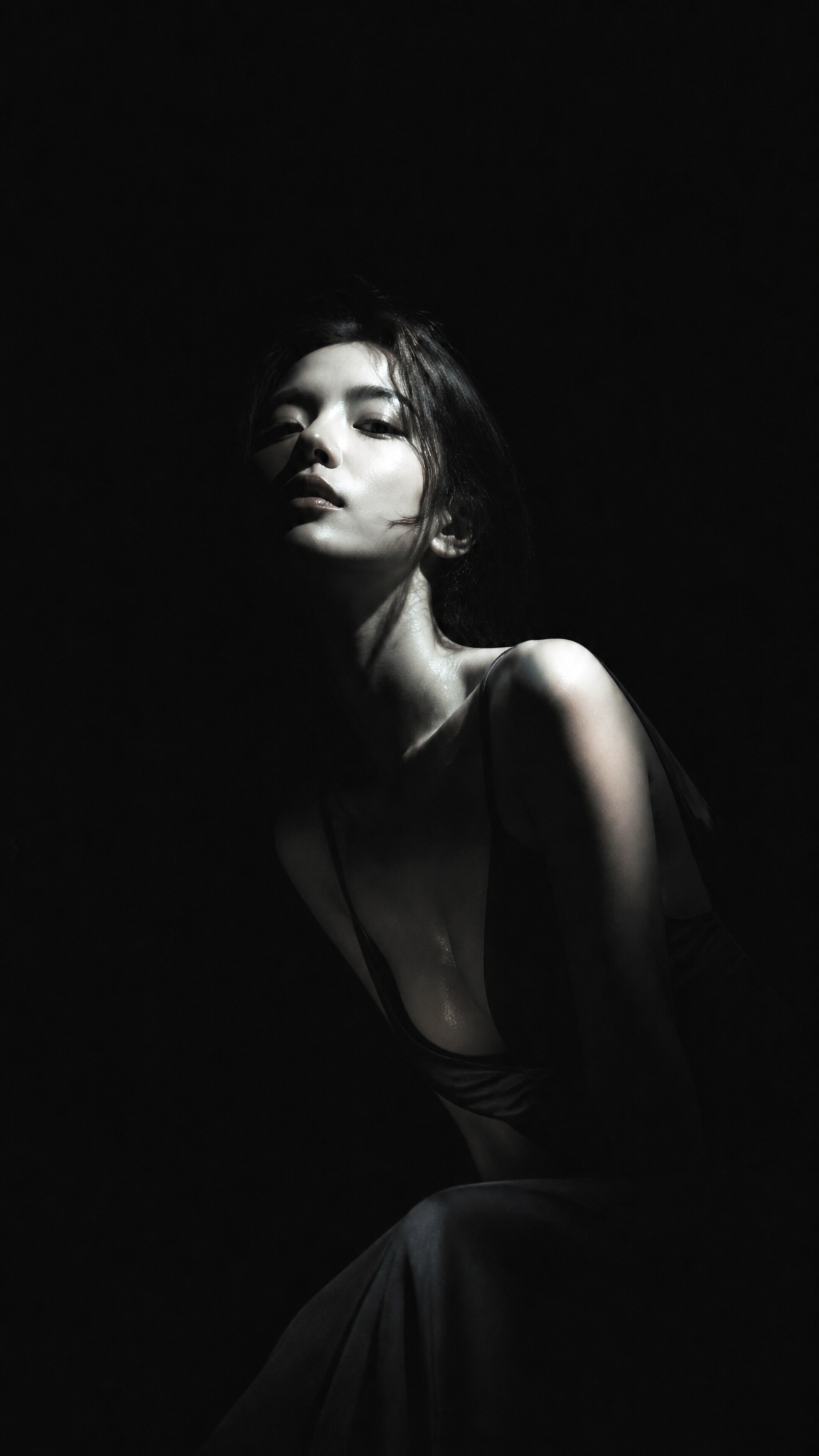 暗黑极简冷光半写实插画，主体为身穿深色低领长裙的漂亮韩国女明星，眼神冷峻，面容俊俏，纯黑背景，大面积黑场吞没画面，侧上方冷白硬光局部照亮主体，…