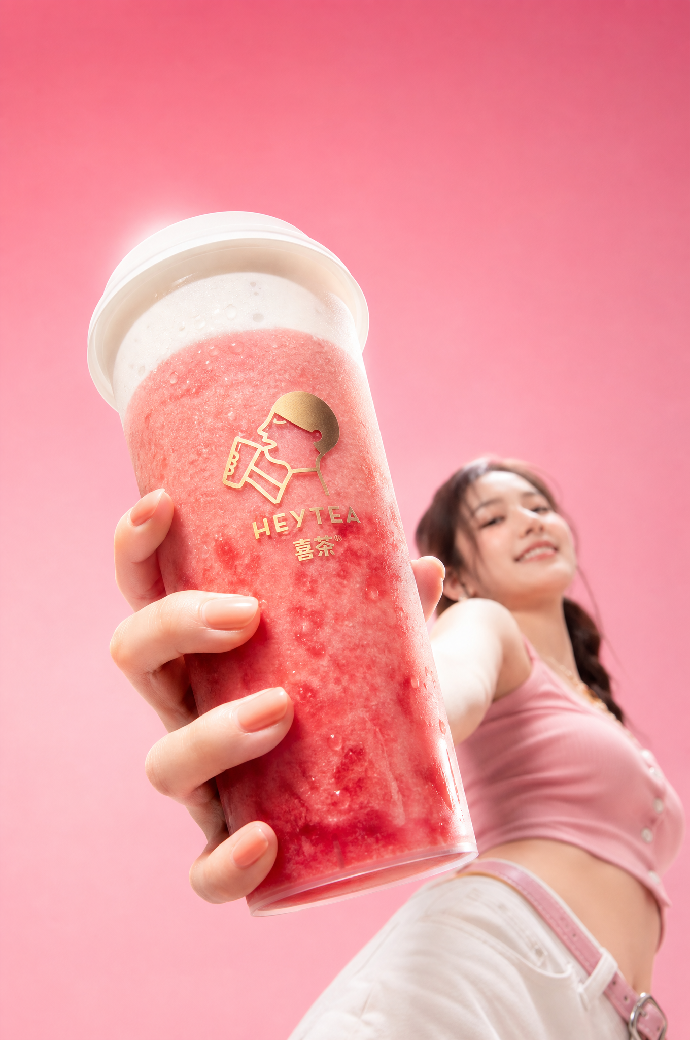 喜茶芝芝莓莓 + 亚洲美女 | 粉桃色渐变背景 [镜头] 极端广角低机位仰拍 人物 镜头从模特下方往上打，前景的手 + 喜茶芝芝莓莓，被极度放…