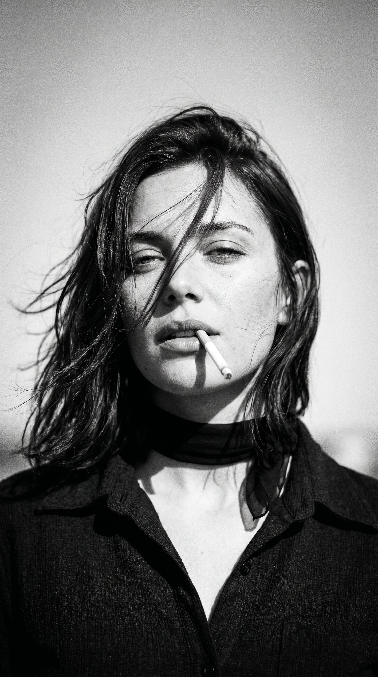 Create a 1970s black-and-white close-up portrait in a windswept outdoor…
